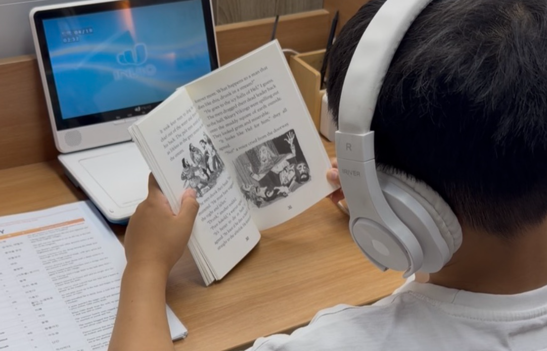 학생이 헤드폰을 끼고 영어 원서를 읽는 모습