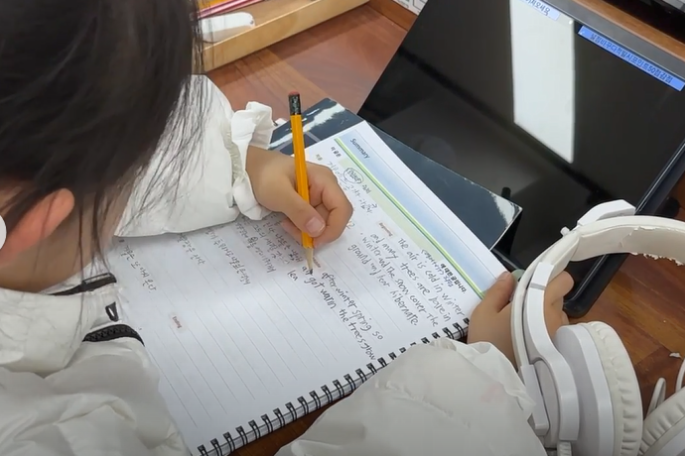 학생이 읽은 내용을 노트에 영어로 요약해 쓰는 모습